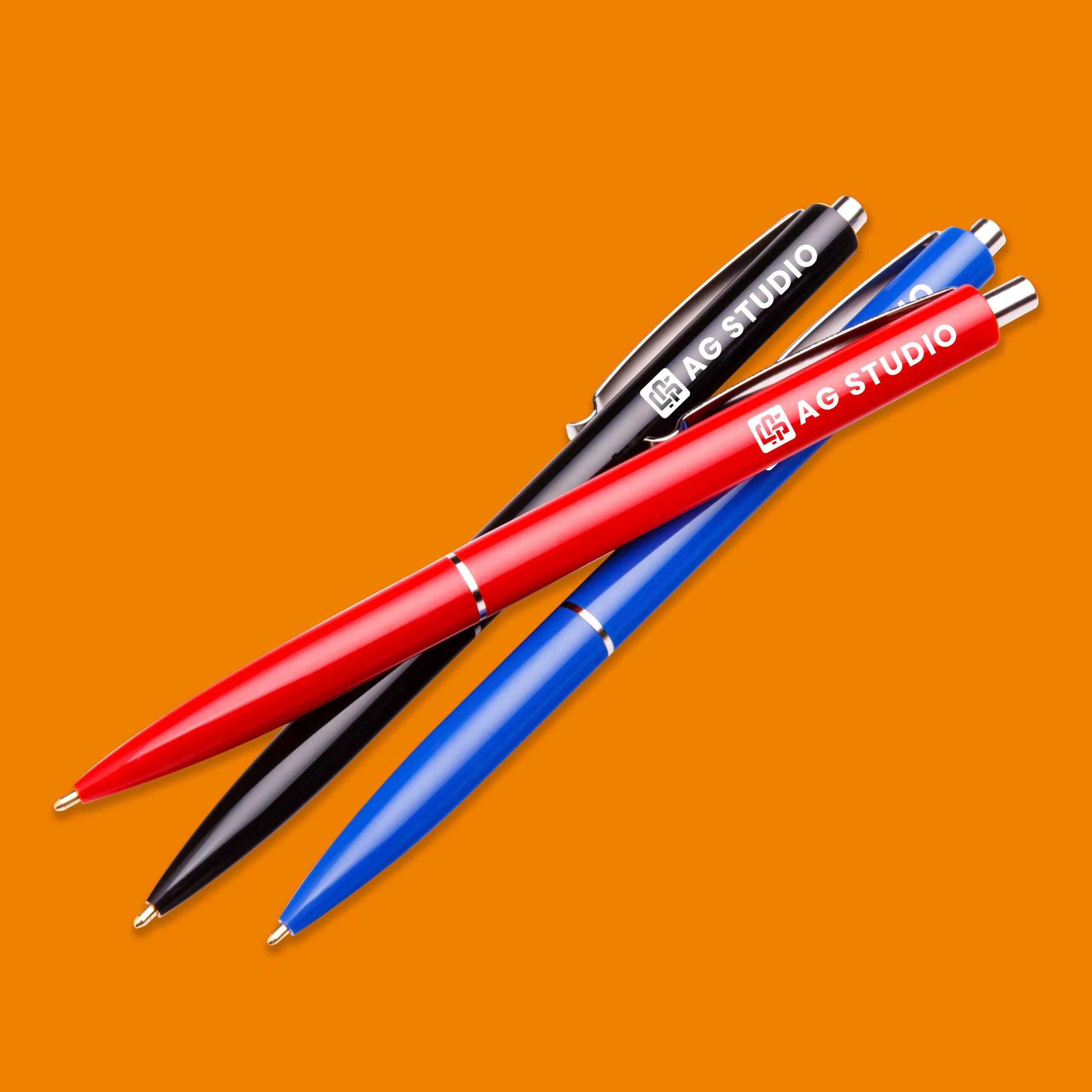 Three pens resting on a vibrant orange background, showcasing their sleek design in Edmonton, AB