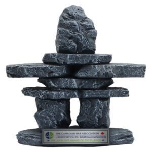 Large stone Inukshuk‑style award sculpture with textured stacked rocks and engraved base plate in Alberta, CA