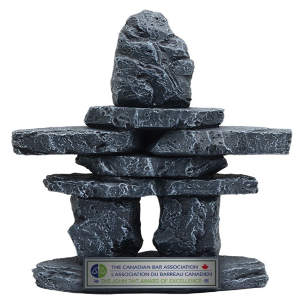 Large stone Inukshuk‑style award sculpture with textured stacked rocks and engraved base plate in Alberta, CA