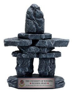 Small stone Inukshuk‑style award sculpture with textured stacked rocks and engraved base plate in Alberta, CA