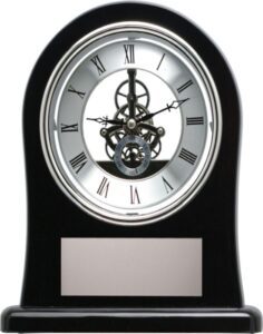 Black skeleton clock with exposed inner gears, Roman numeral dial and engraving plate displayed in Alberta, CA